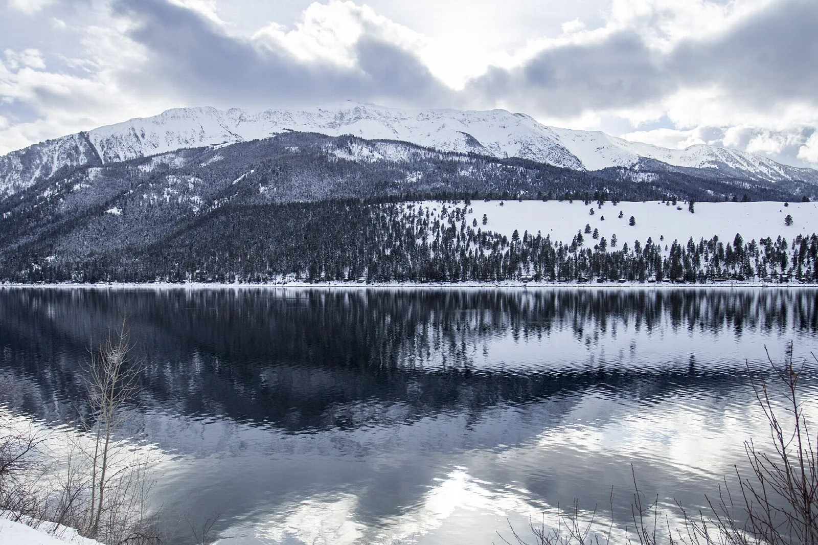Mountains and forest reflected in still lake water