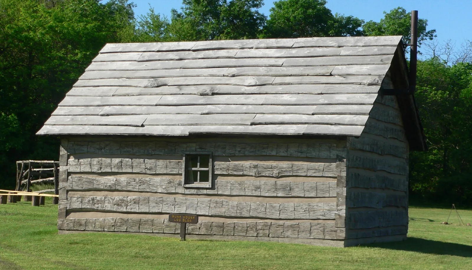 Log building with a shingled roof surrounded by trees