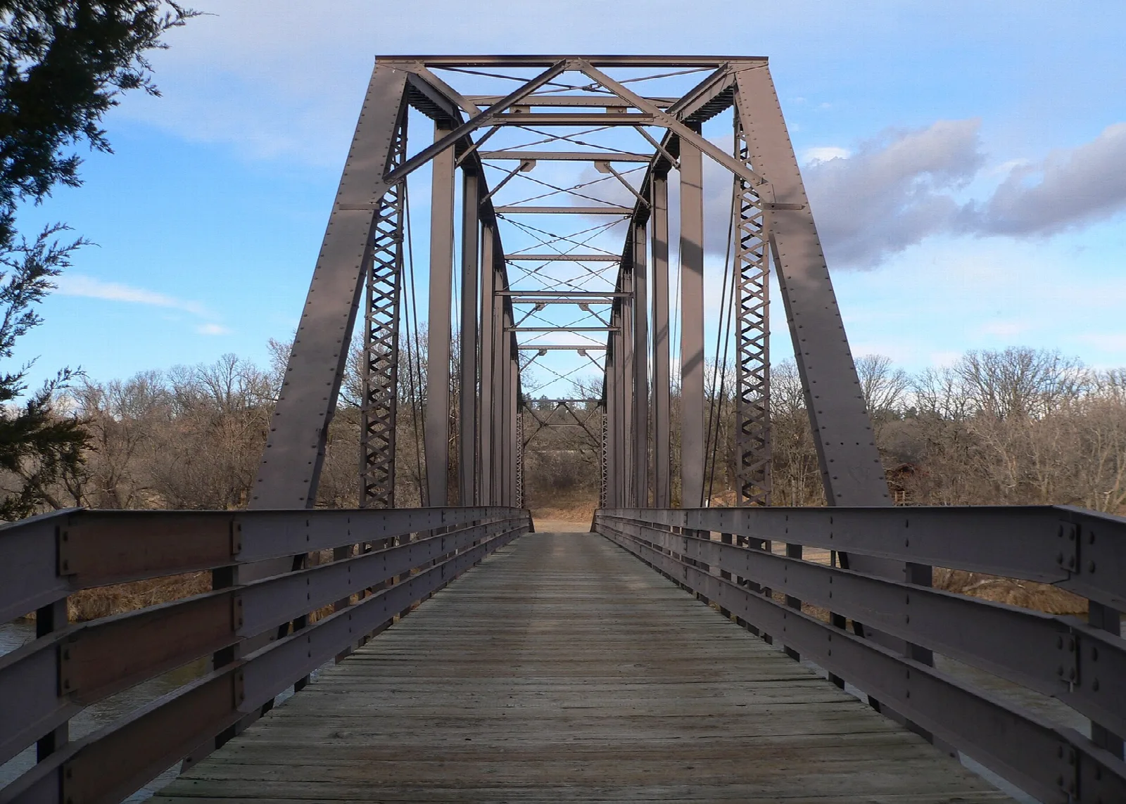 Old steel truss bridge with a wooden deck used as a footbridge
