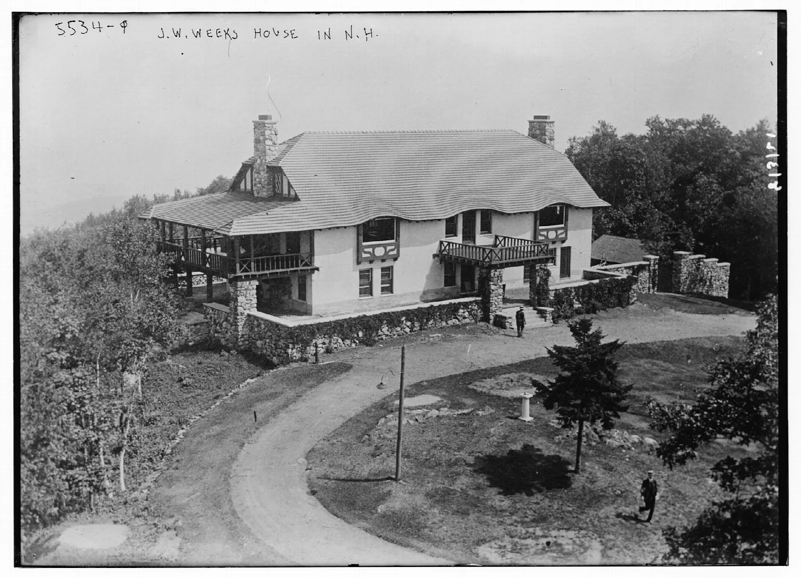 Black and white photo of a large house with a curving drive on a hilltop