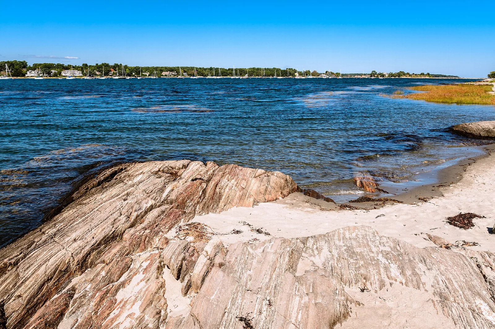 Pink granite ledge meeting a sandy shore and open water
