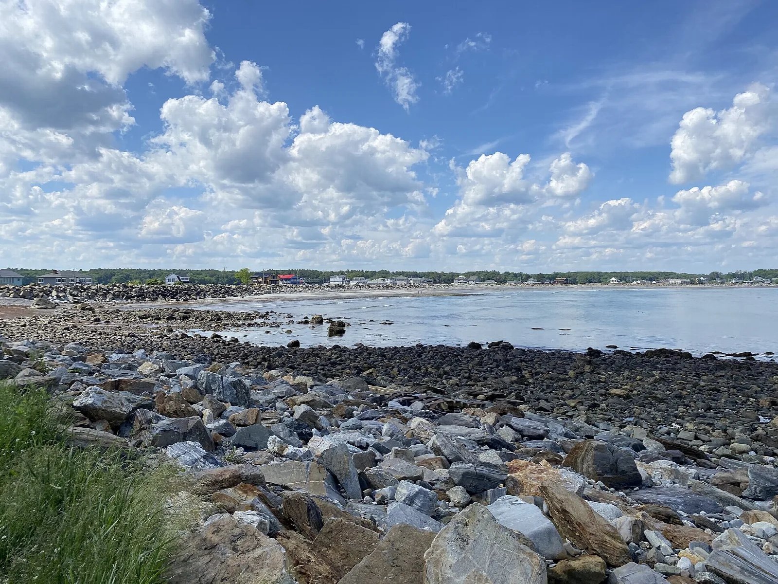 Rocky beach and shoreline looking toward town under a cloudy sky