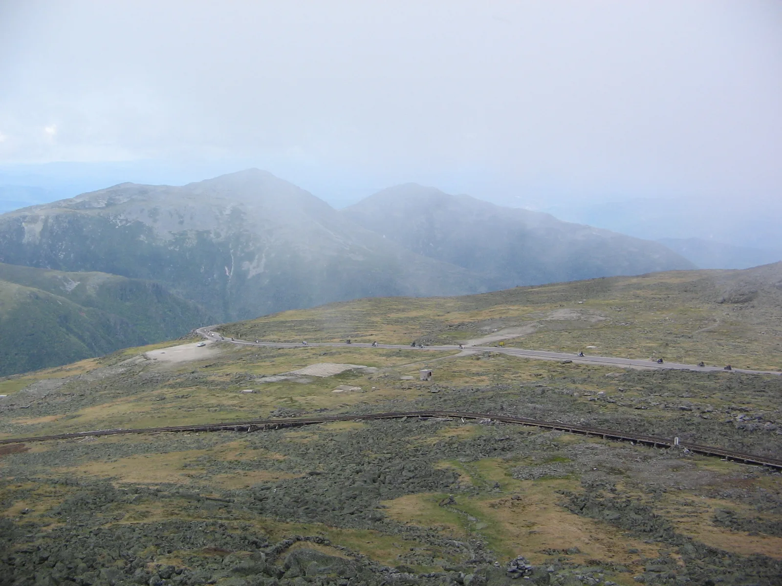 Road winding across a barren mountain slope toward the summit in haze