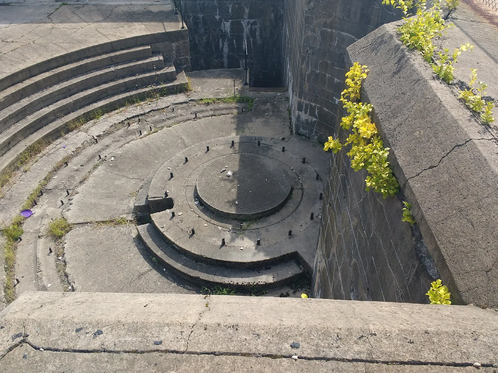 Curved concrete gun emplacement with stepped walls and a round center pit