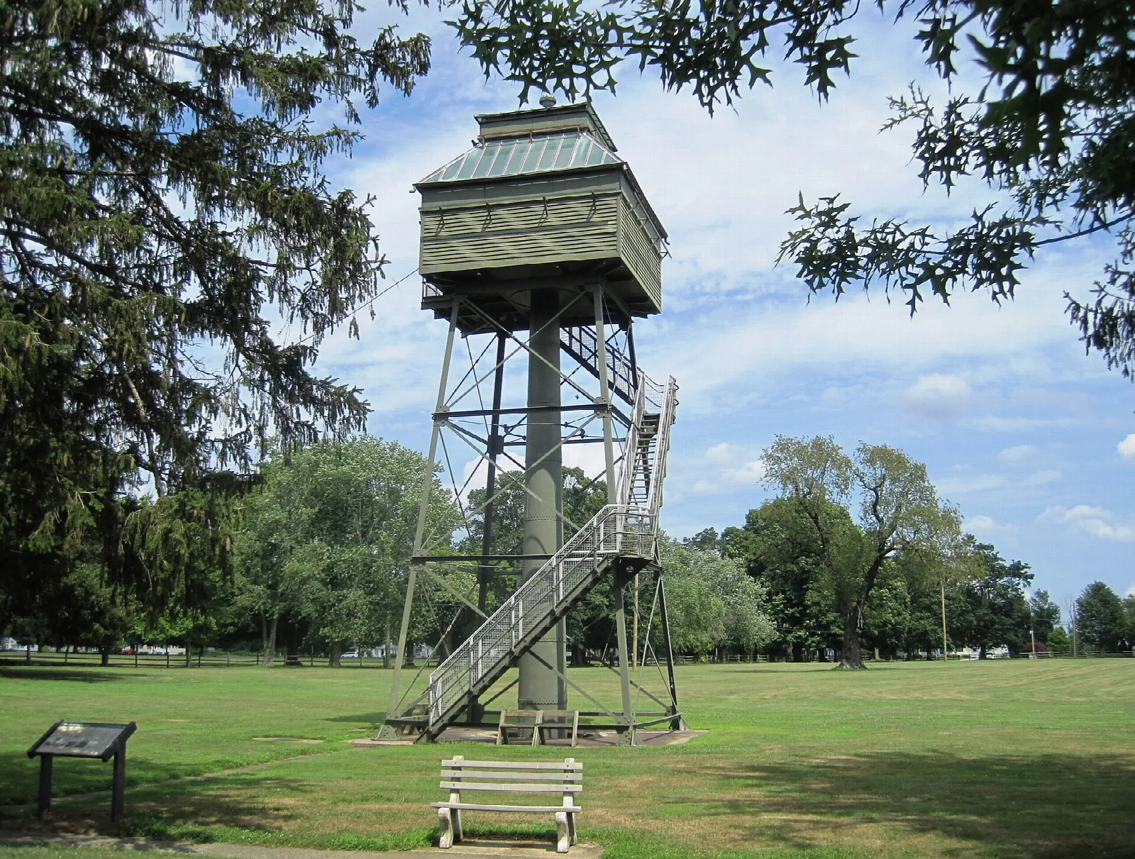 Green-roofed fire control tower on a stair frame above a wide lawn