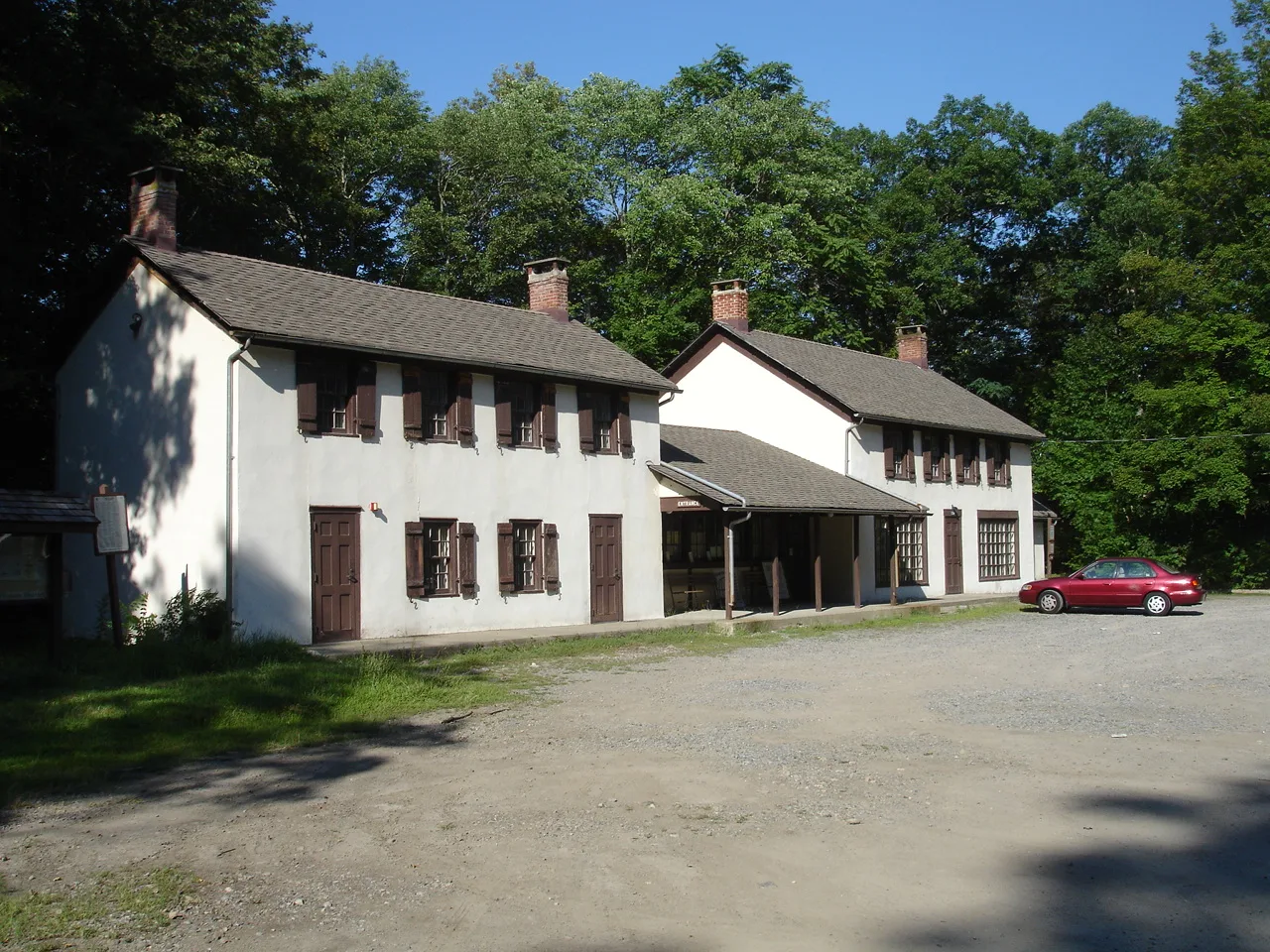 Long white farmhouse-style building beside a gravel lot