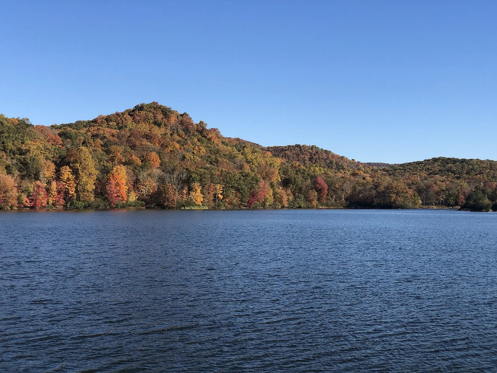 Autumn hillside reflected in blue reservoir water