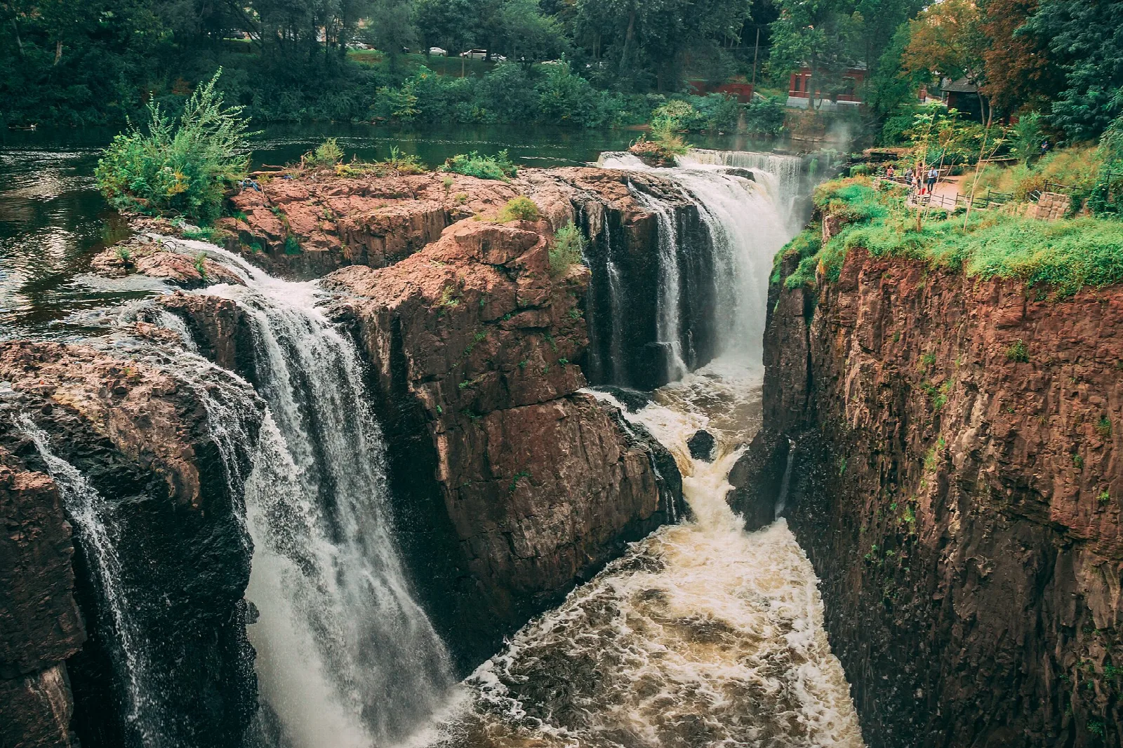 Two waterfalls spilling over red rock cliffs into a gorge