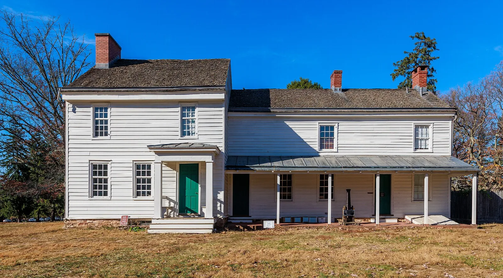 White two-story farmhouse with a porch under a blue sky