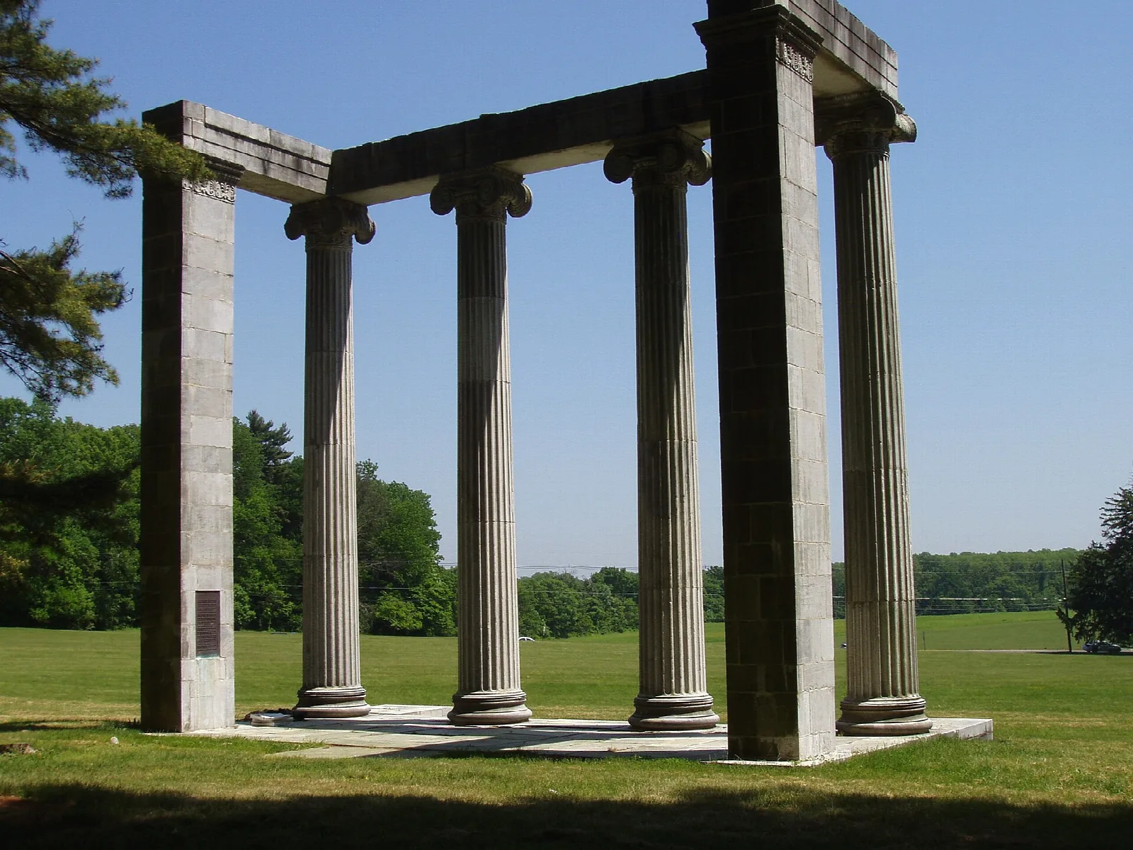 Stone colonnade of tall columns on an open lawn