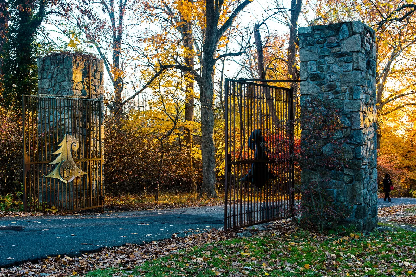 Stone gate posts and iron gate among orange fall trees