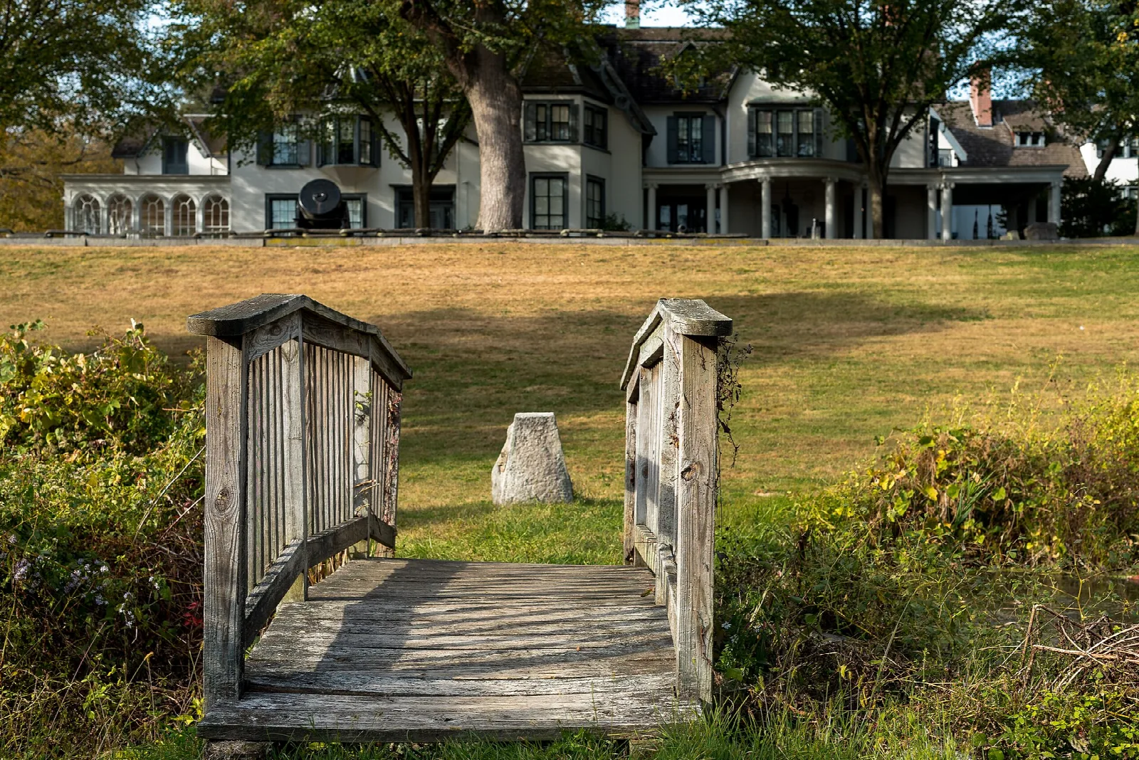 Wooden footbridge leading toward a large manor house