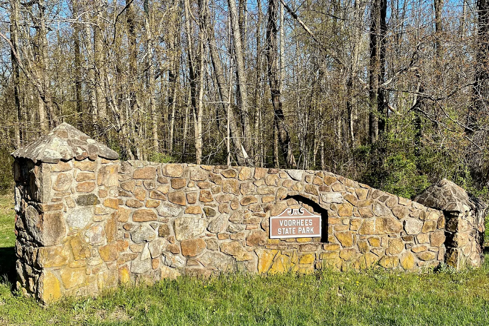 Low stone wall with a park sign beside a grassy field