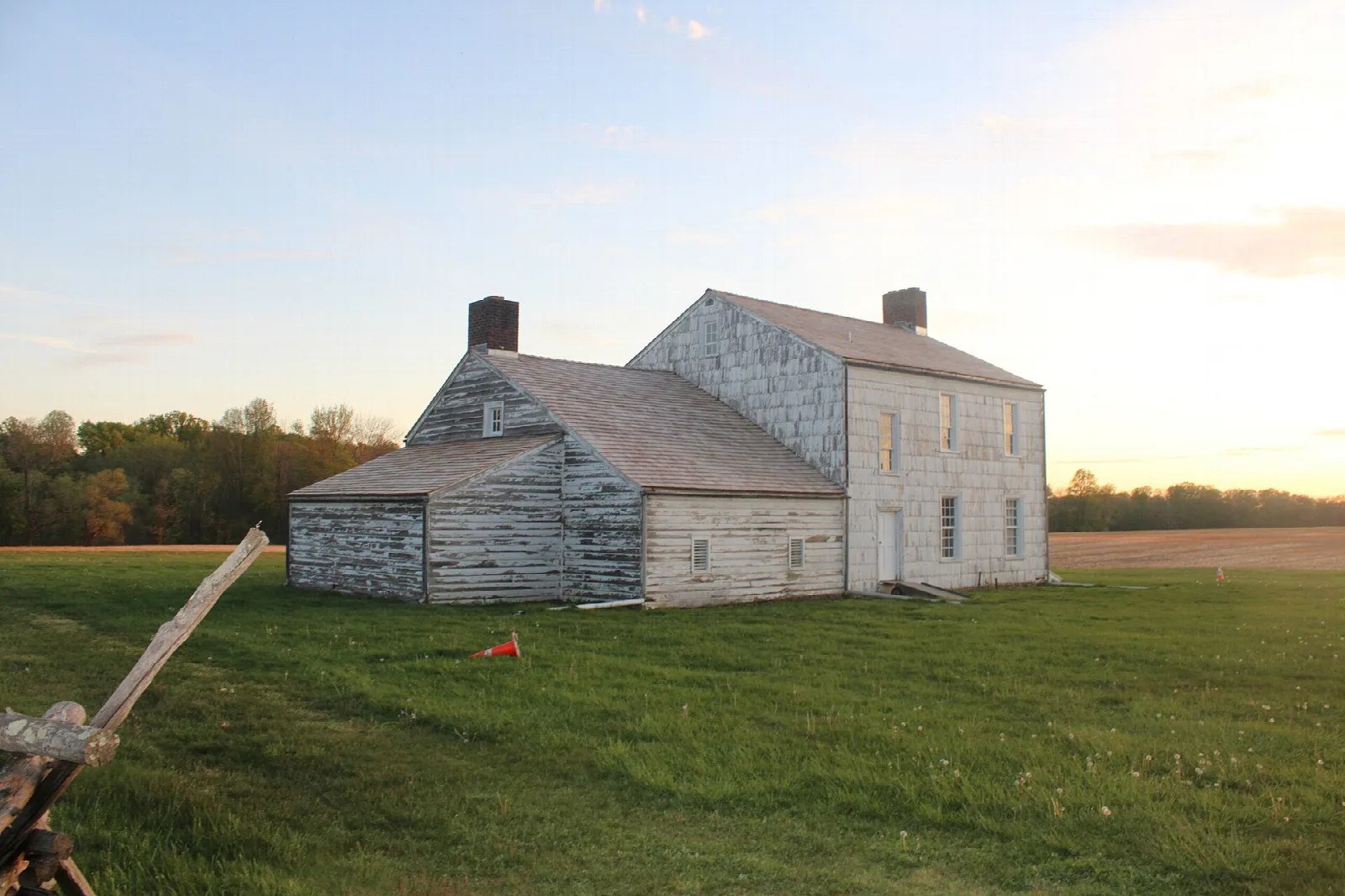 Old white farmhouse in a field at sunset