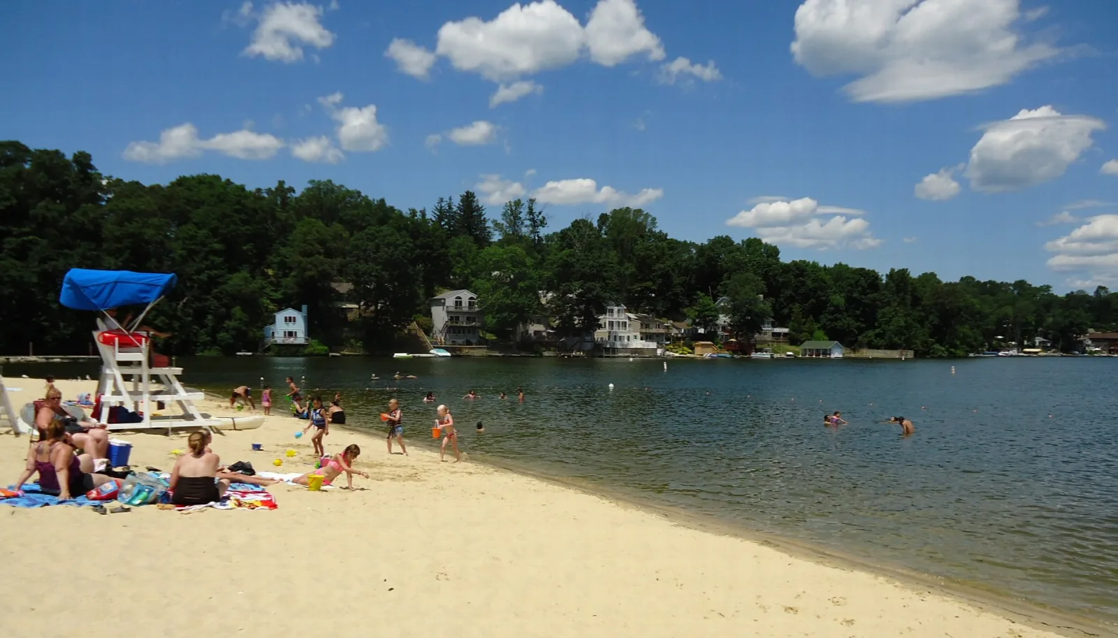 Sandy beach with swimmers and a lifeguard stand on a lake