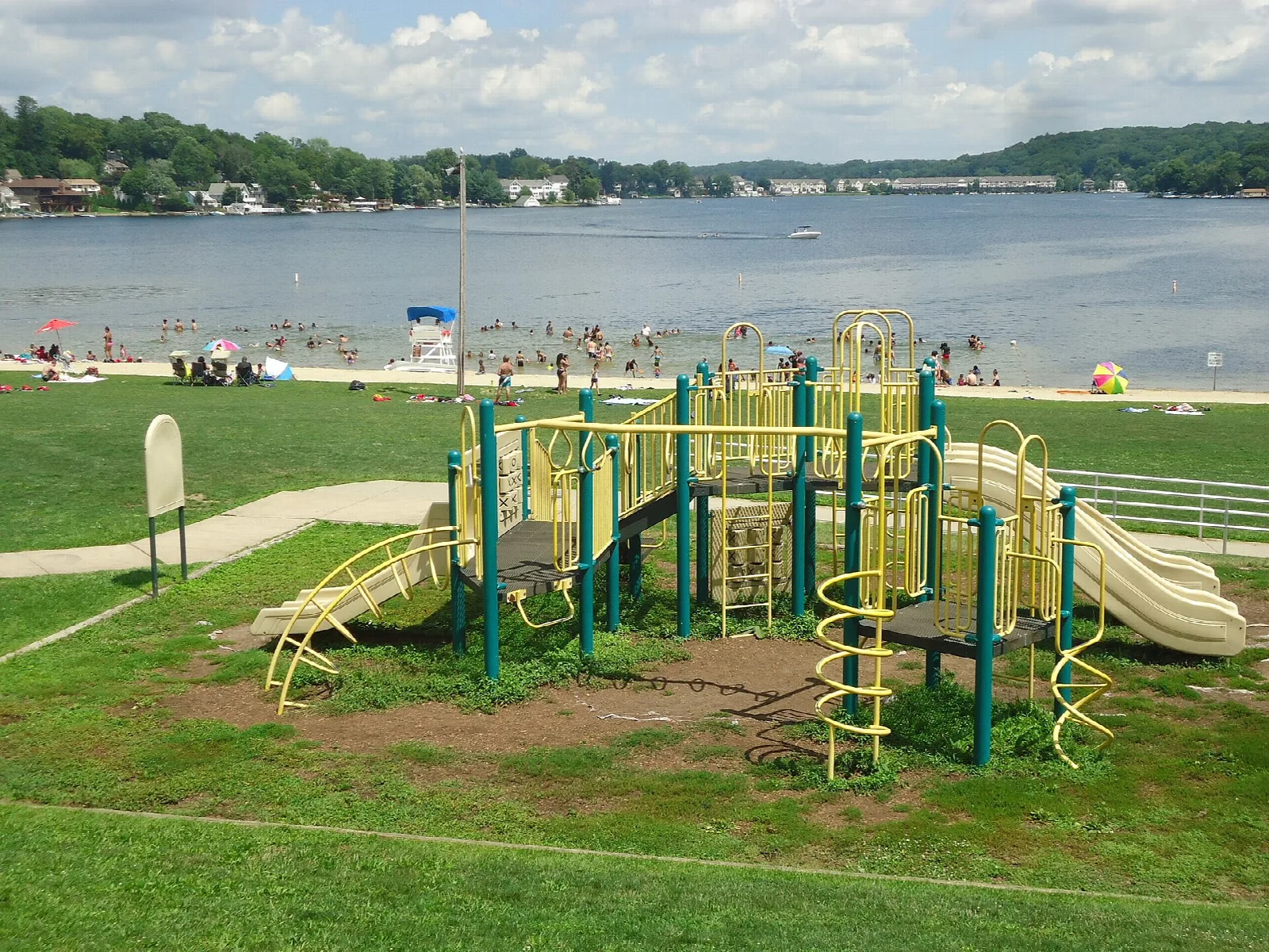 Playground by the lake with swimmers in the distance