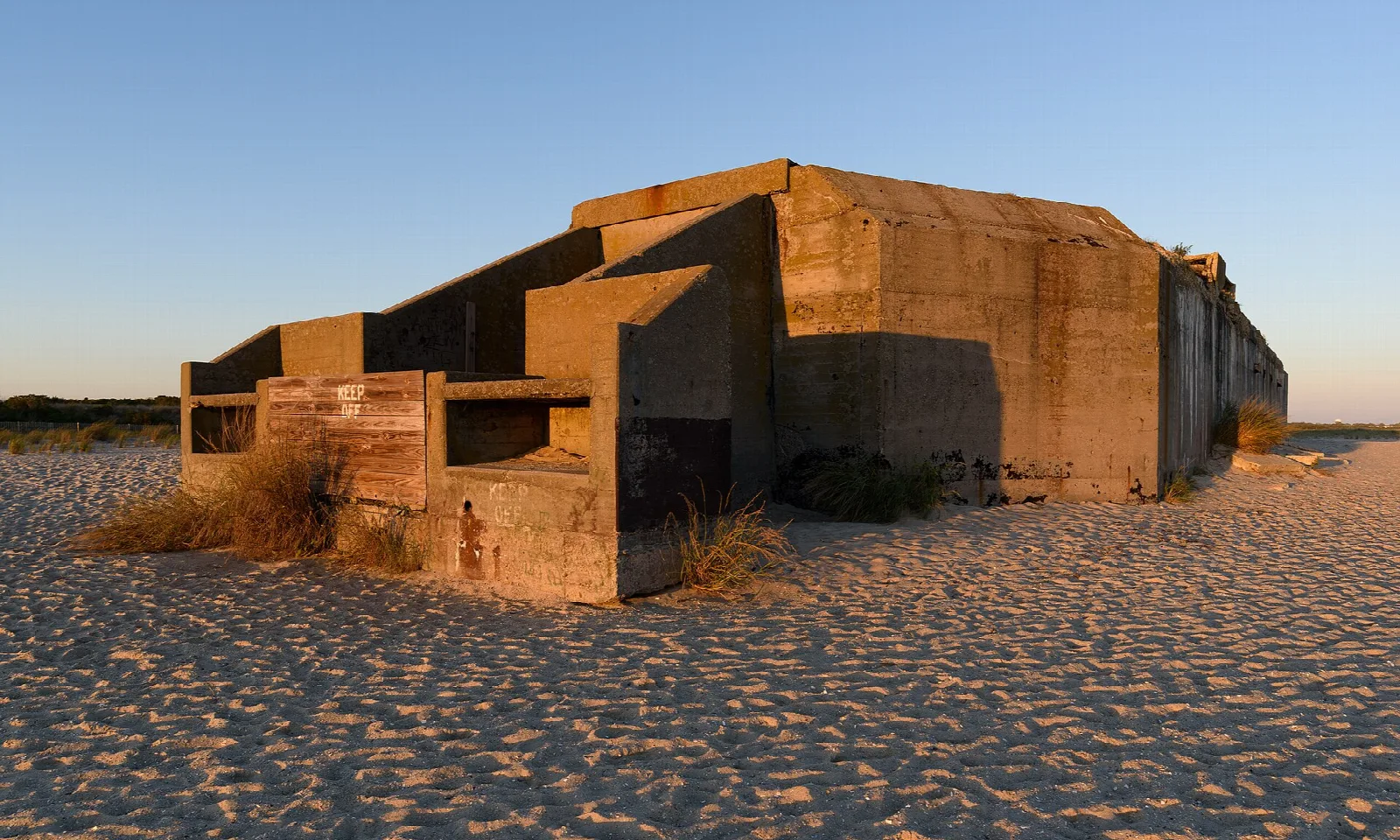 Concrete bunker on a sandy beach at sunset