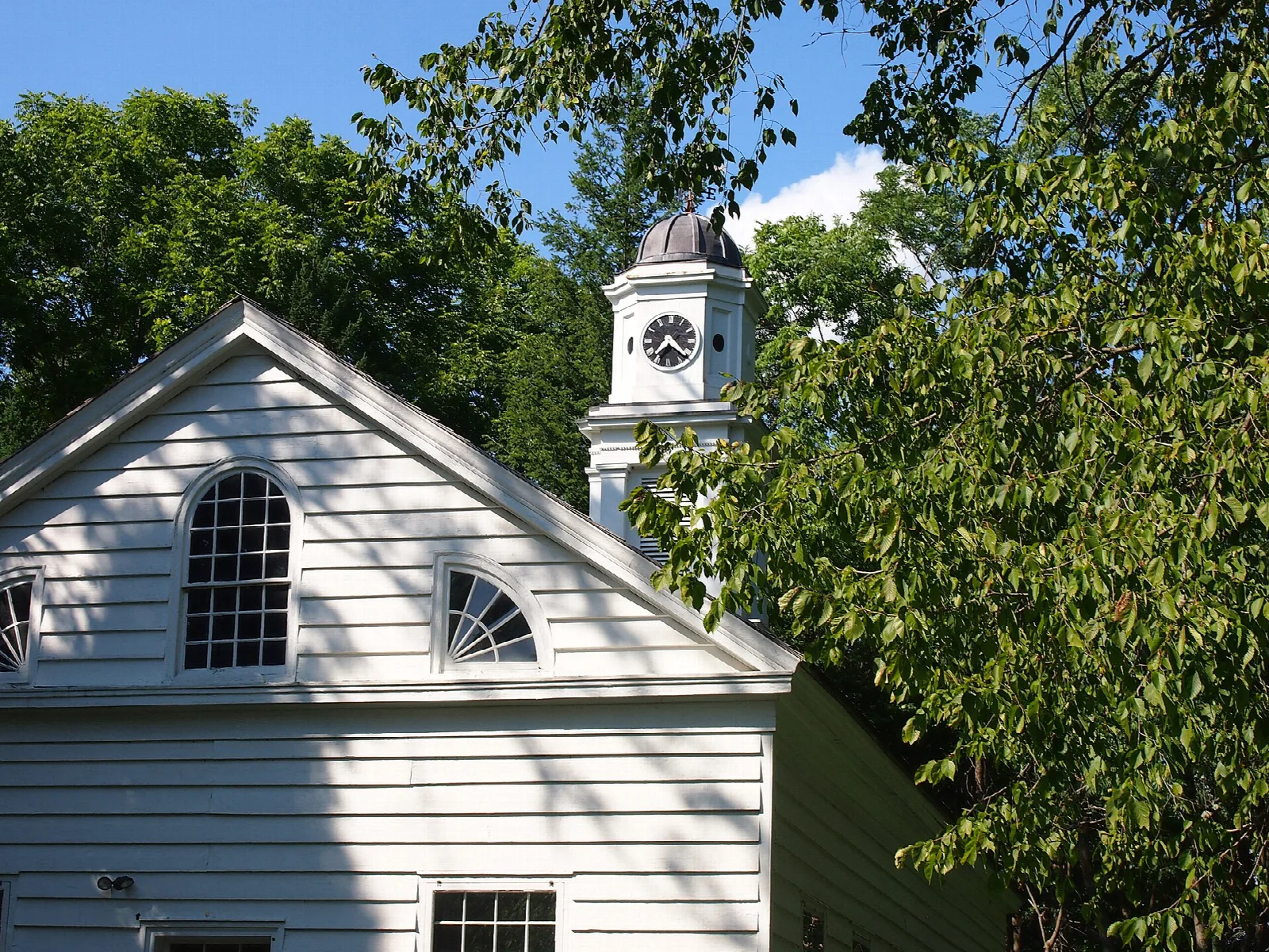 White chapel with a clock tower and tall trees
