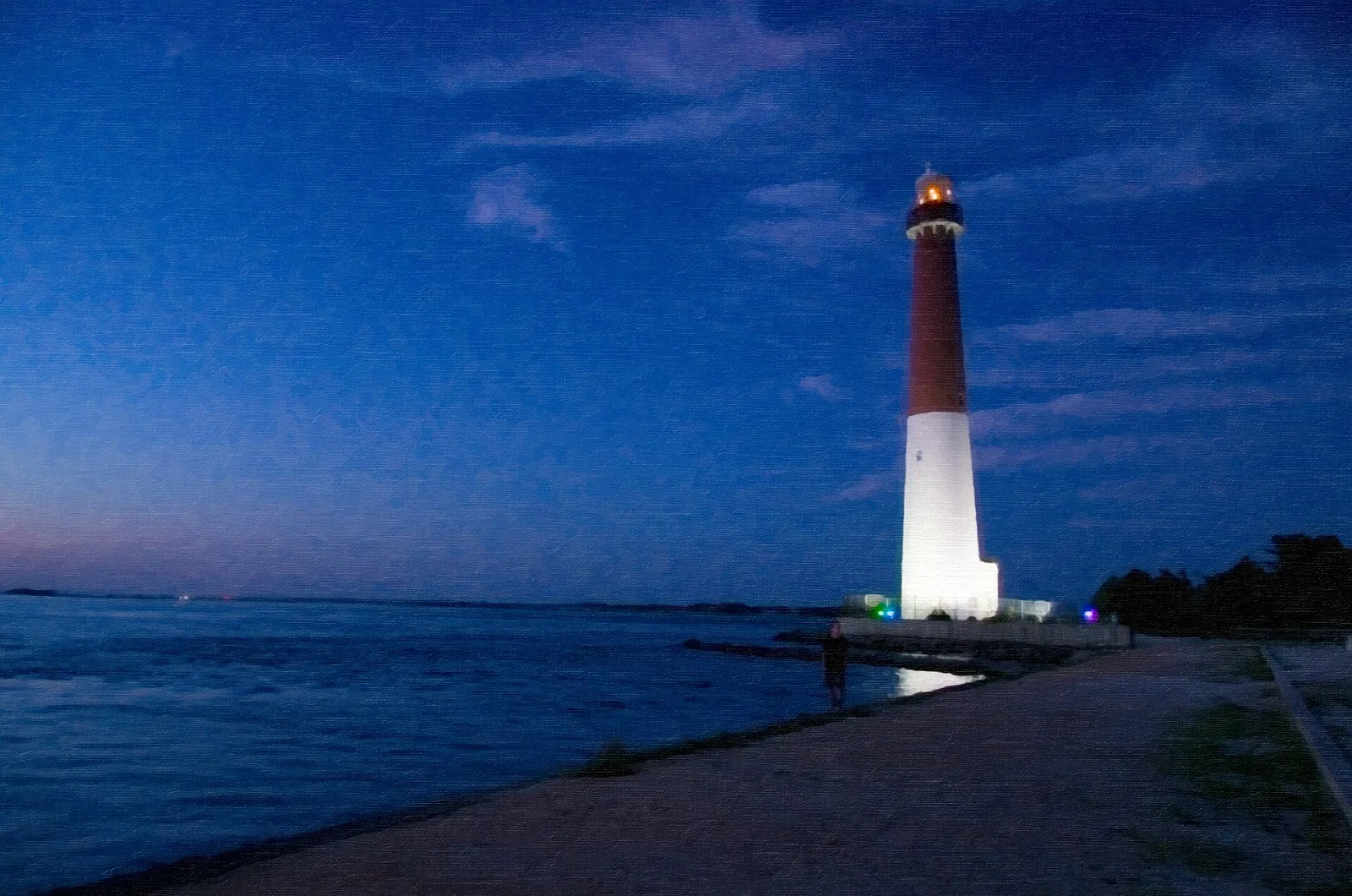 Lighthouse lit at dusk beside the water