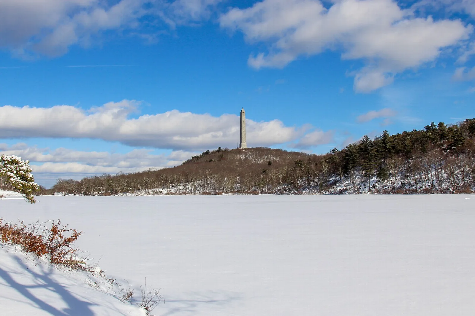 Tall monument on a ridge above a snow-covered lake