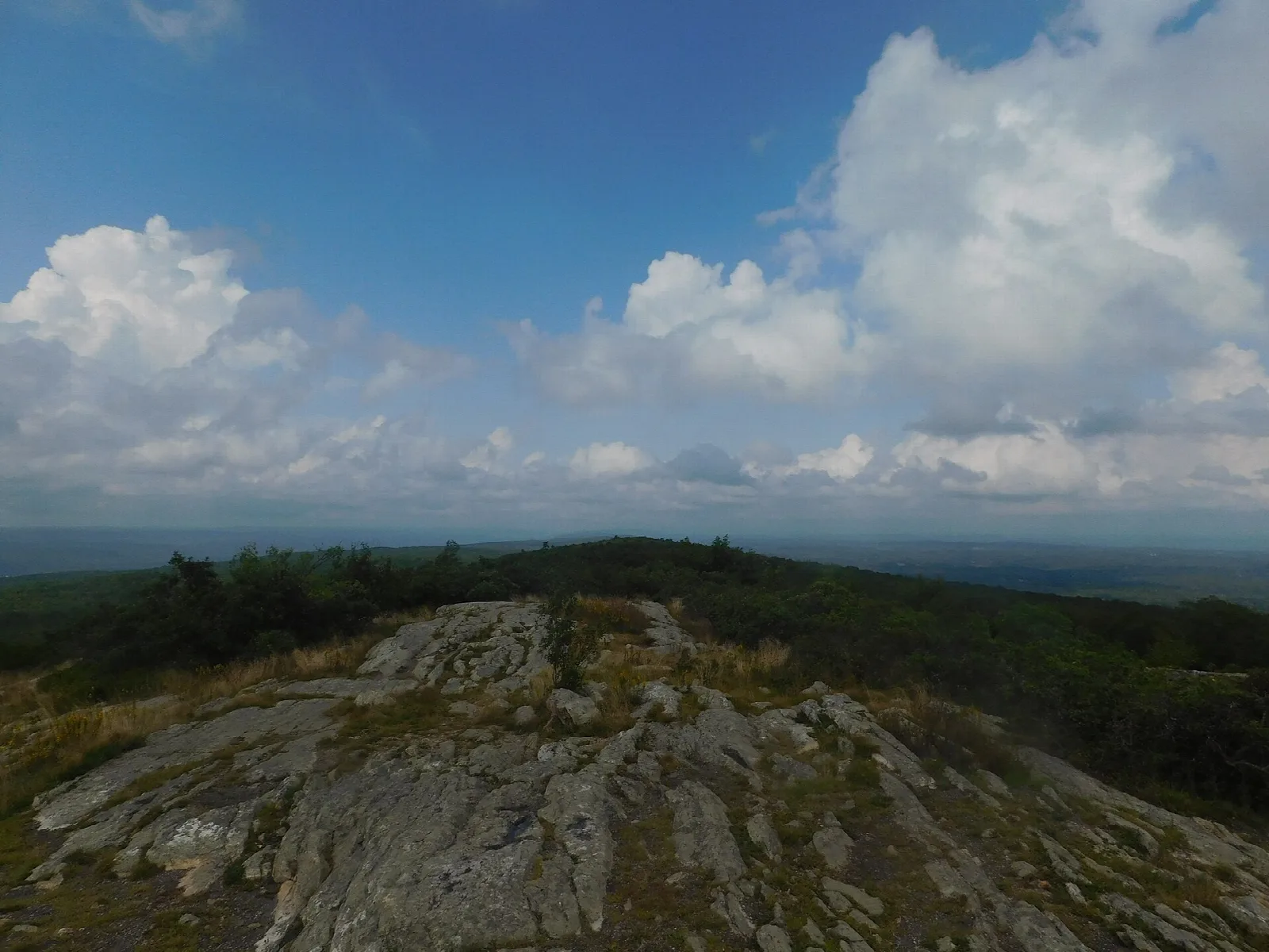 Bare rock outcrop with a wide hazy valley view