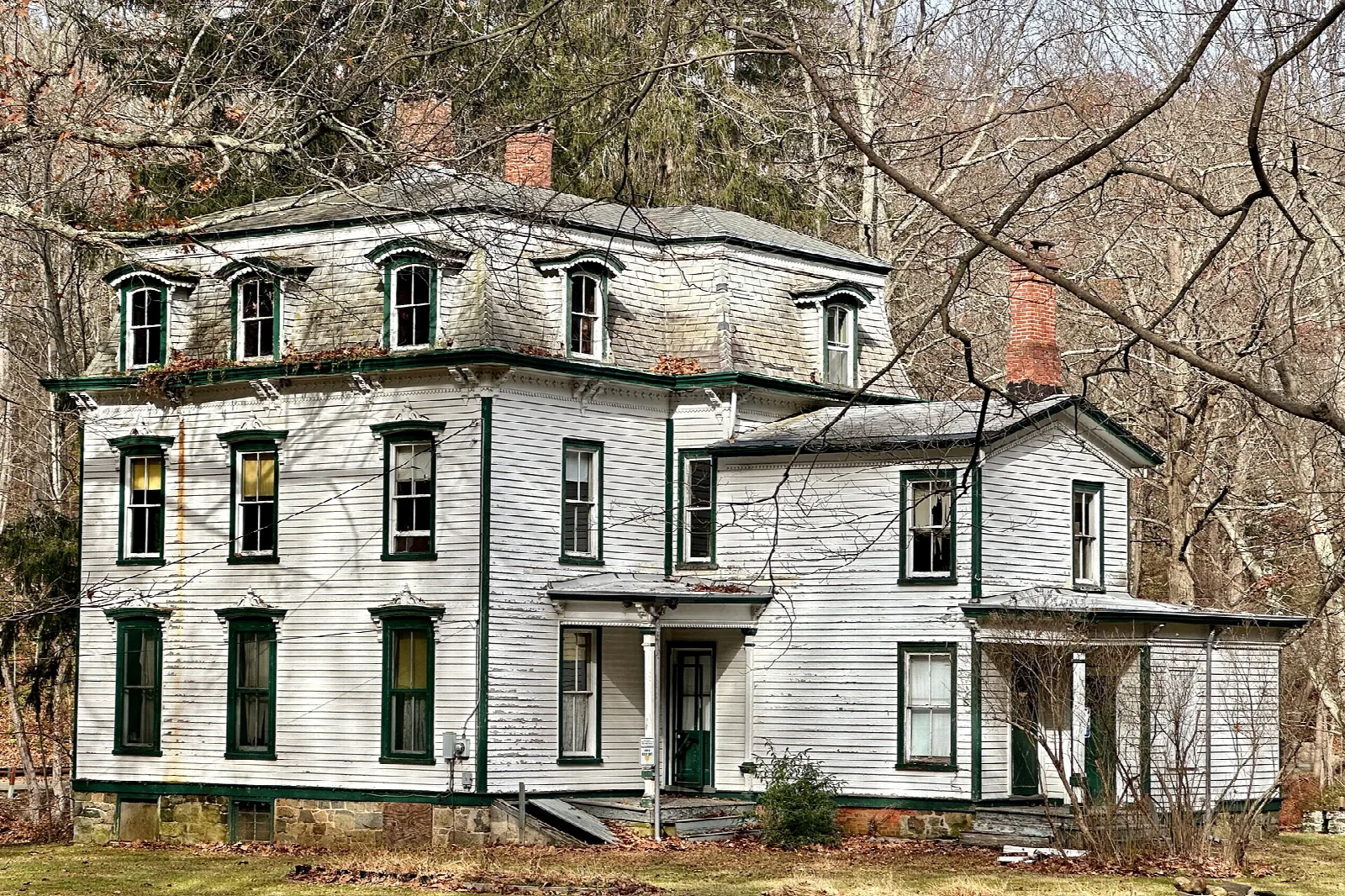Large white two-story historic house among trees