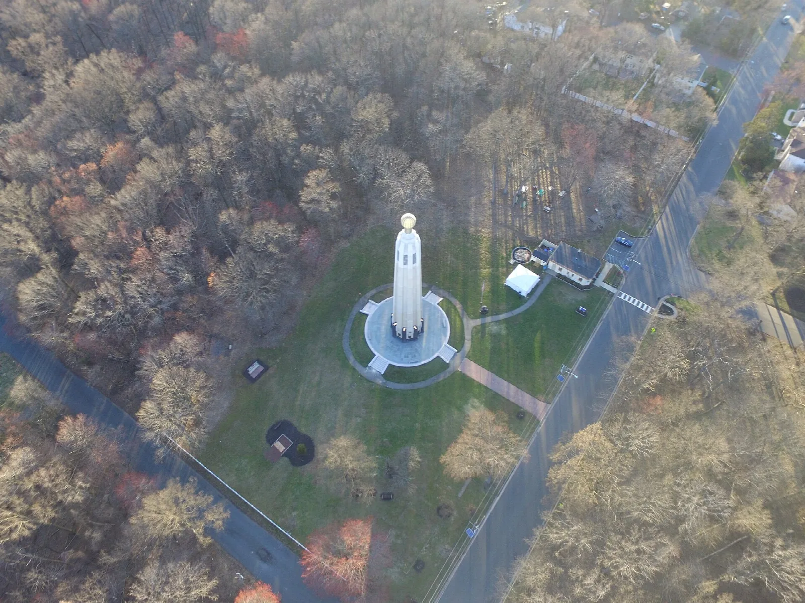 Aerial view of a white tower on a lawn surrounded by woods