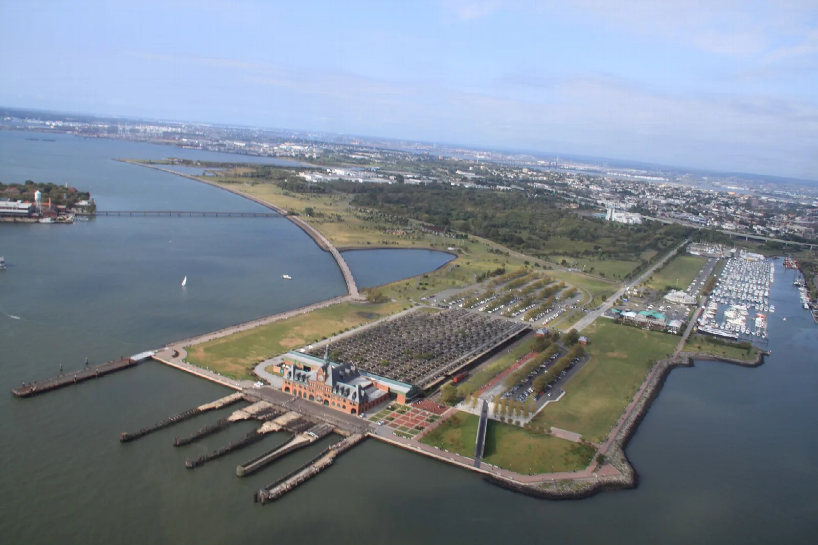 Aerial view of a waterfront park with a large old terminal building and marina