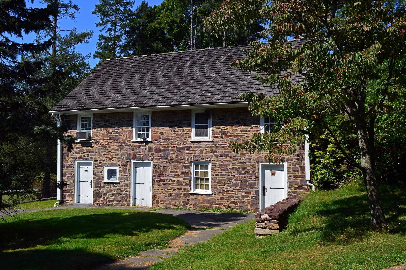 Stone barn with white doors in a green yard
