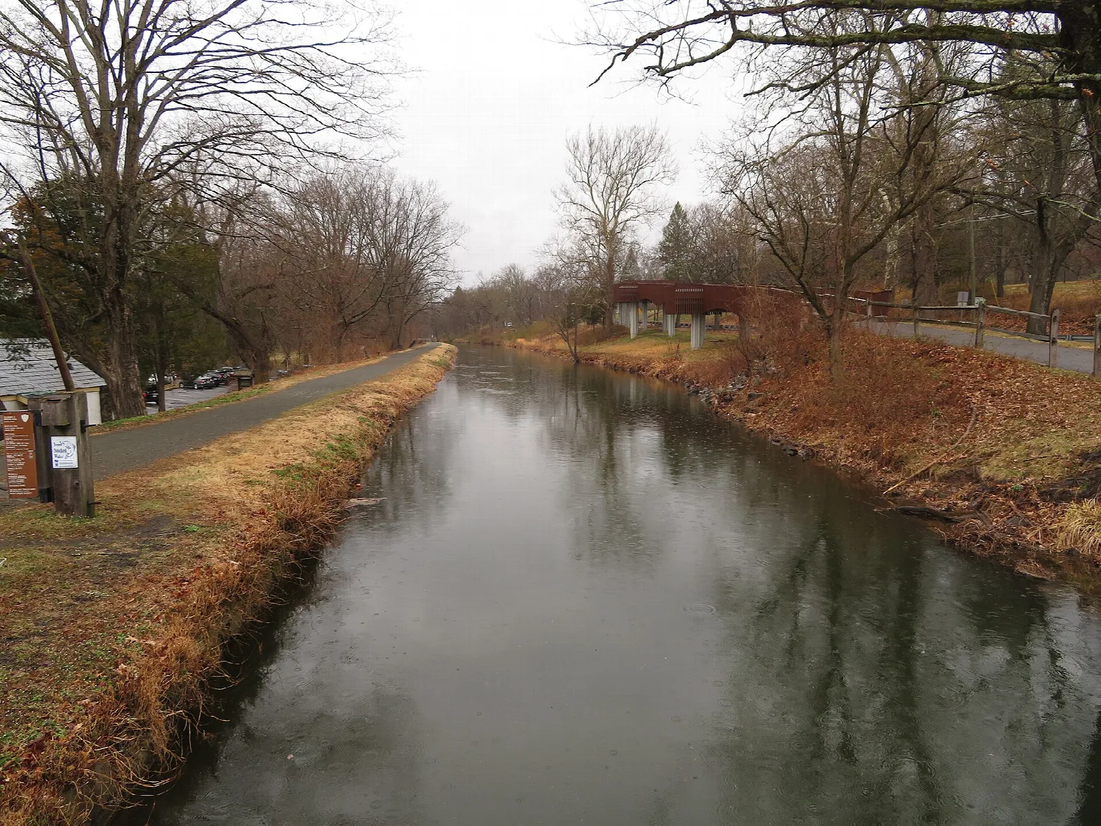 Still canal between grassy banks and bare trees