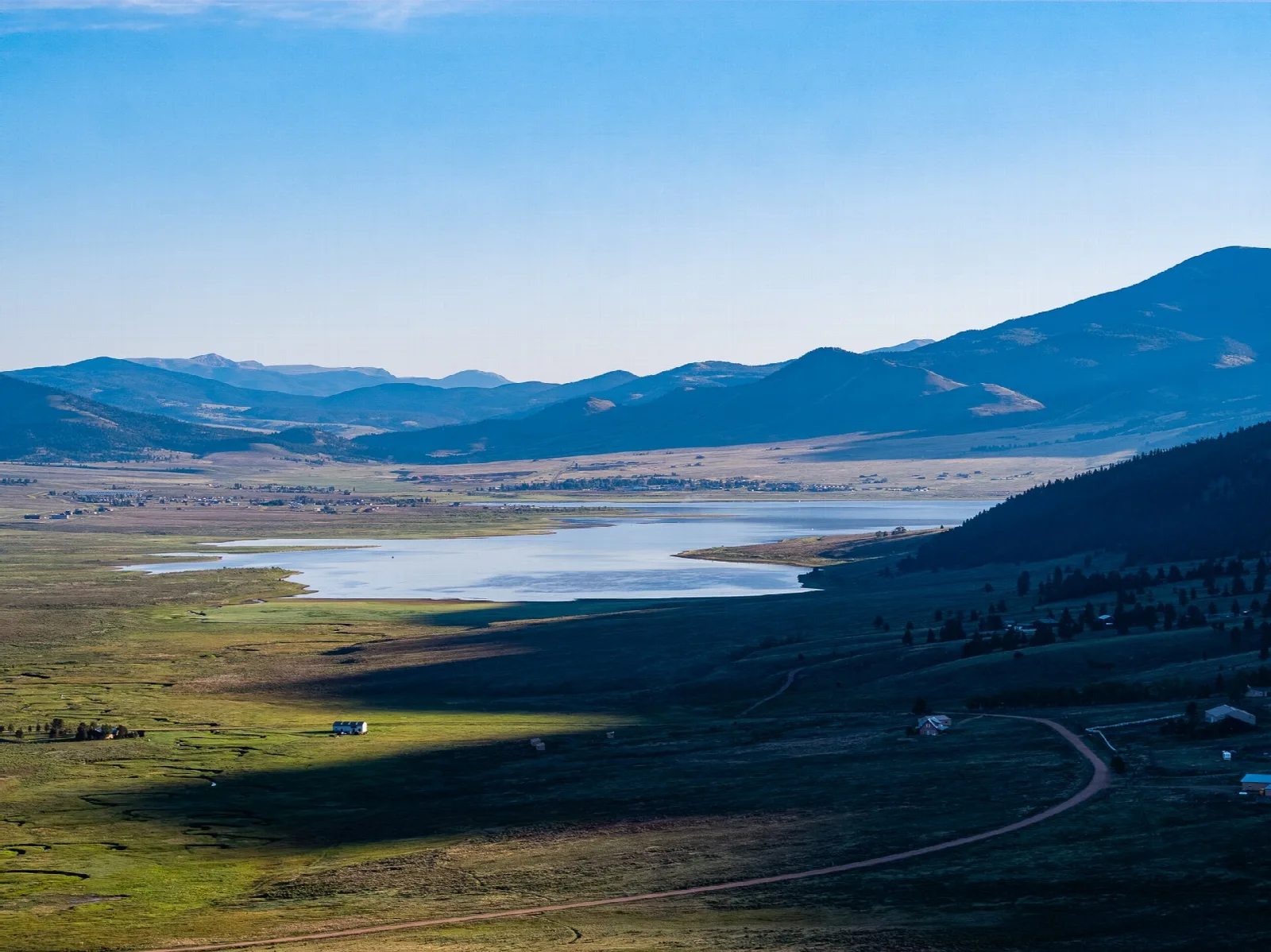 Aerial view of a lake in a mountain valley with a road along the shore