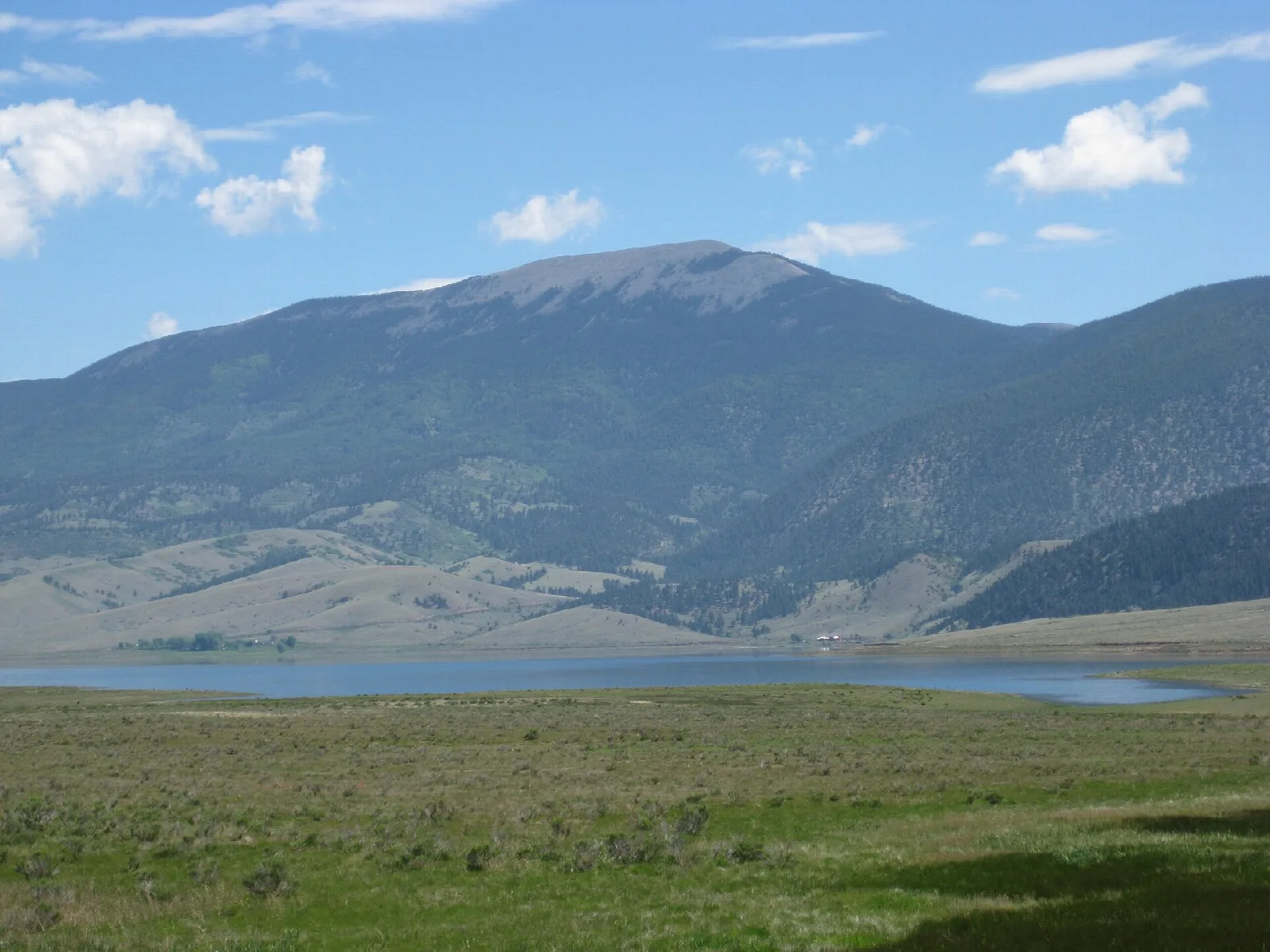 Wide grassy valley with a lake and a large mountain behind