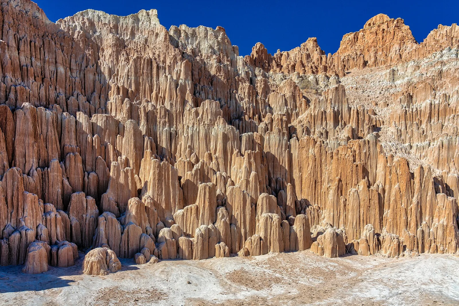 Tall eroded clay spires rising above a pale valley floor