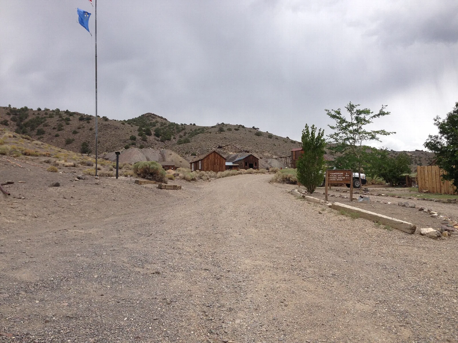 Gravel road entering a small historic town with a flag and trees