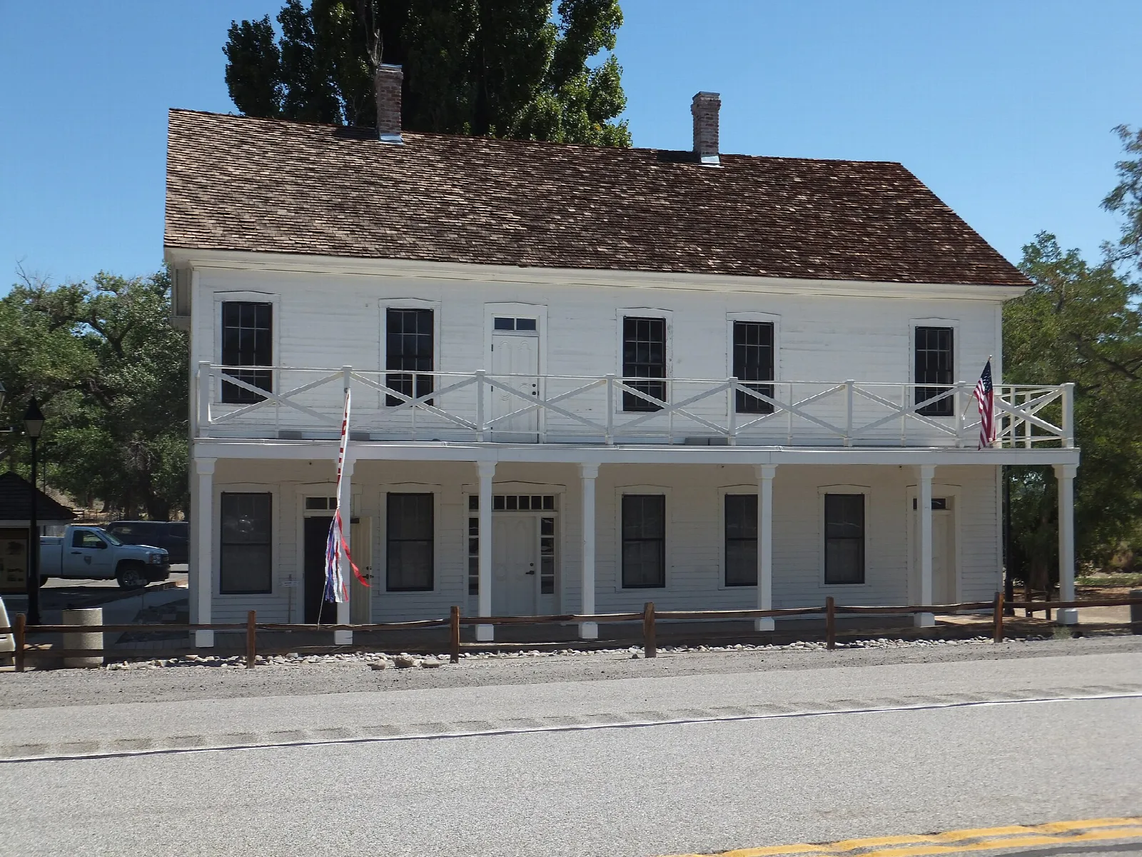 Two-story white building with a balcony beside a road