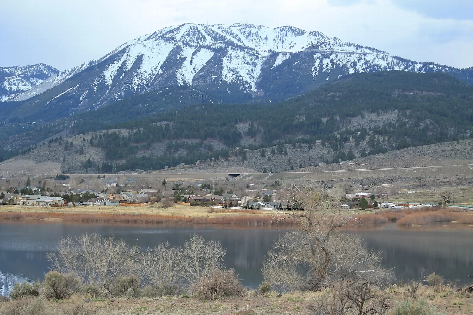 Snow-capped mountain above a small town across a calm lake