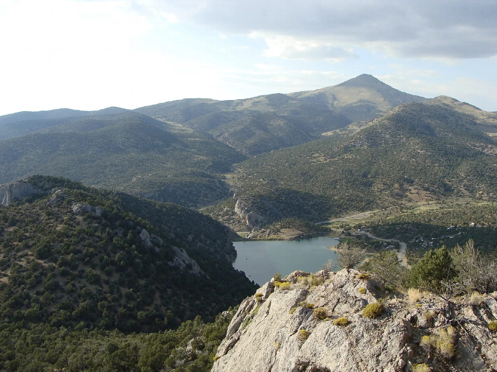 View from a rocky overlook down to a reservoir among forested mountains