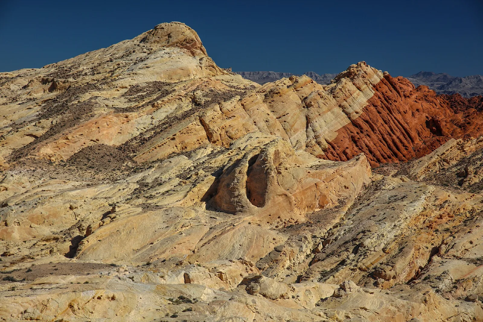 Layered tan and red sandstone slope with a rounded hollow