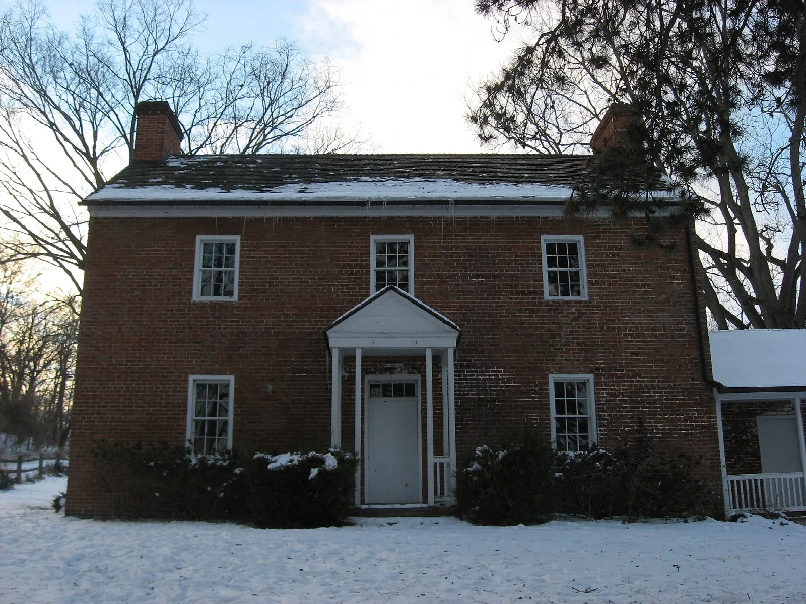Brick two-story house with a porch in snow