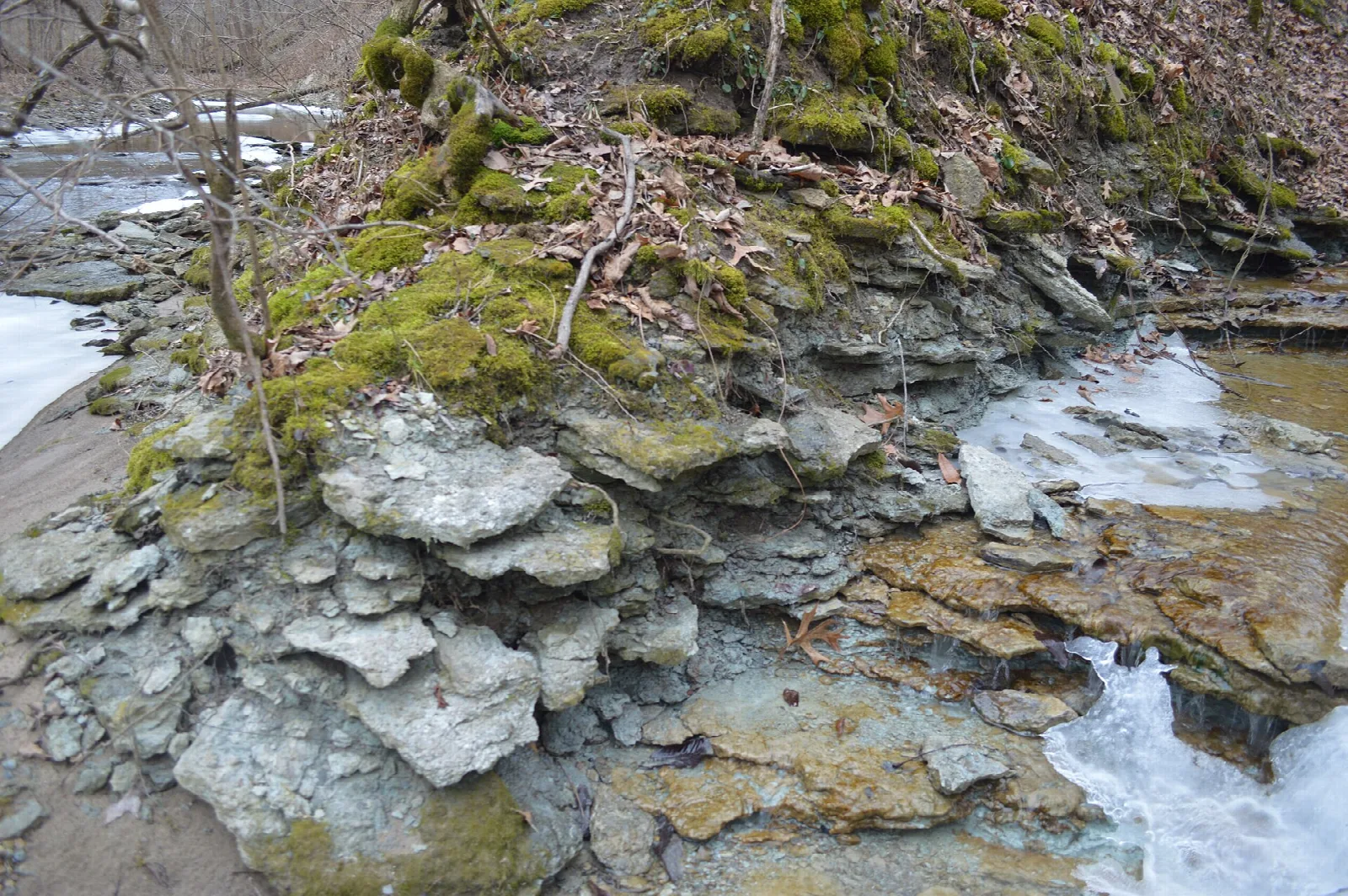 Mossy rock ledge beside an icy creek