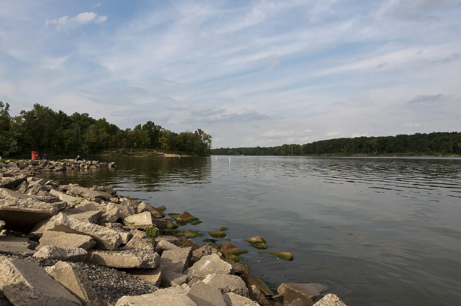 Rock-lined bank on a broad lake with trees across the water