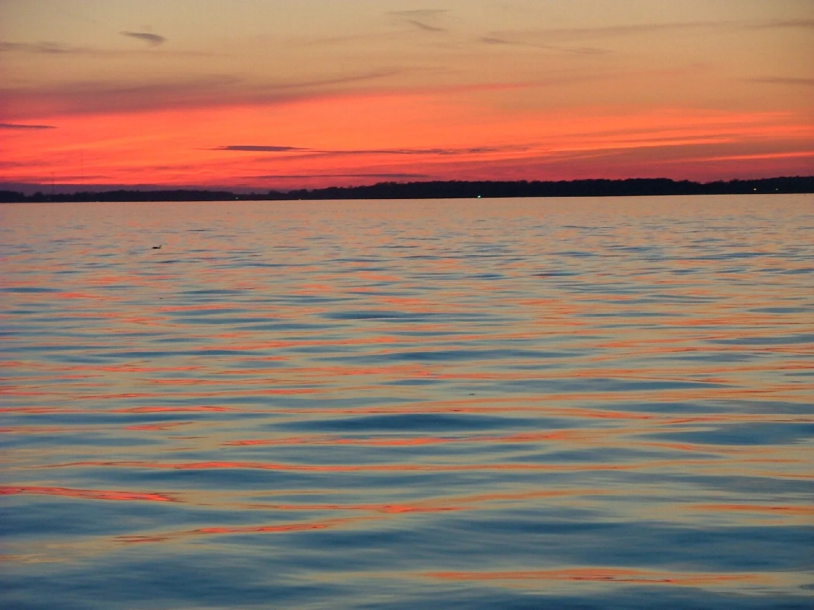 Orange sunset reflected on rippled lake water