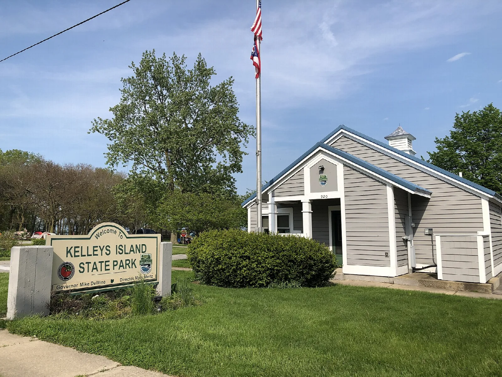 Gray building with a flag beside a Kelleys Island State Park sign