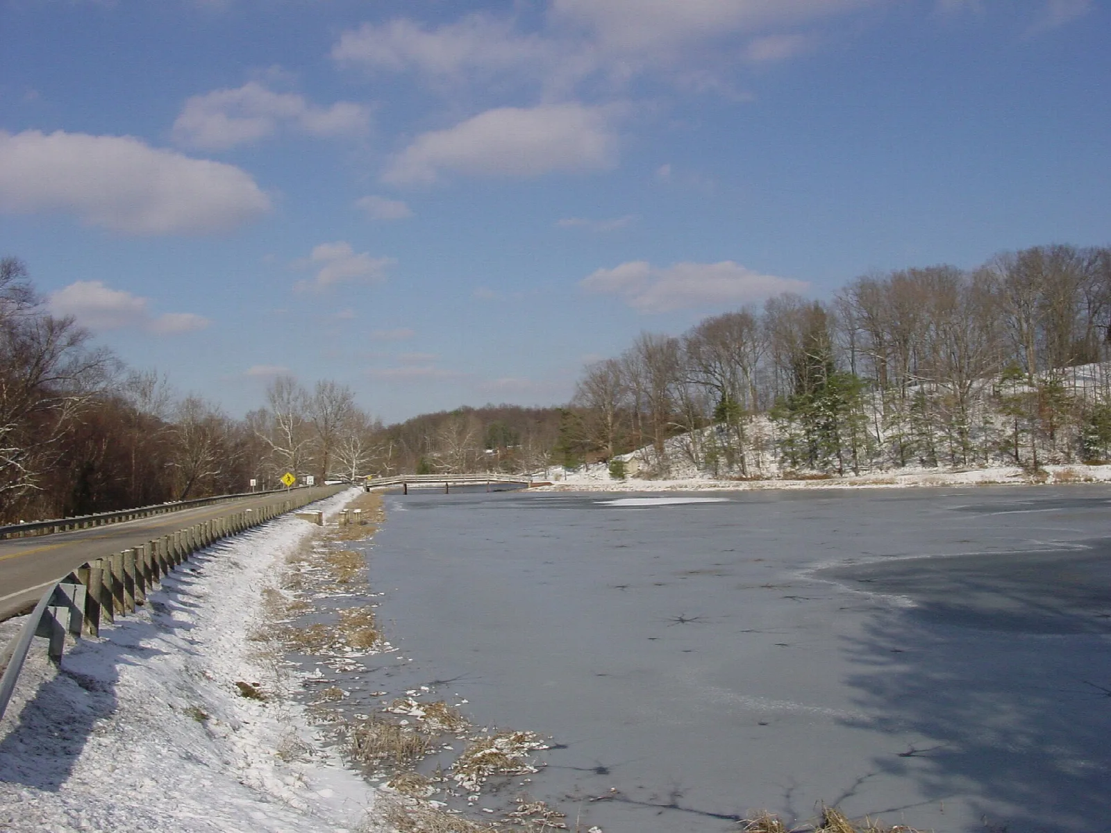 Frozen lake and snowy bank with a bridge and island in winter