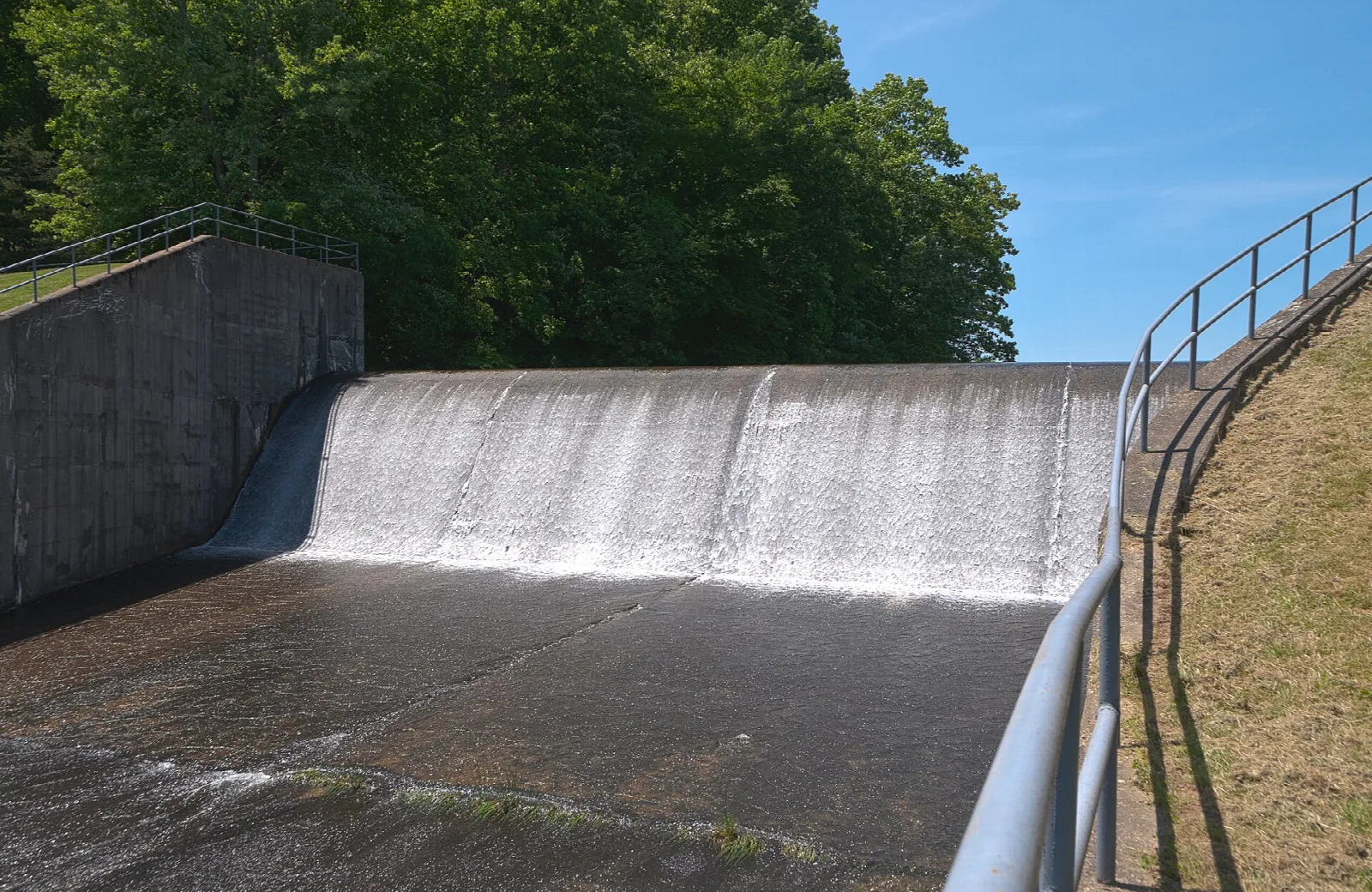Water spilling down a concrete spillway beside a railing