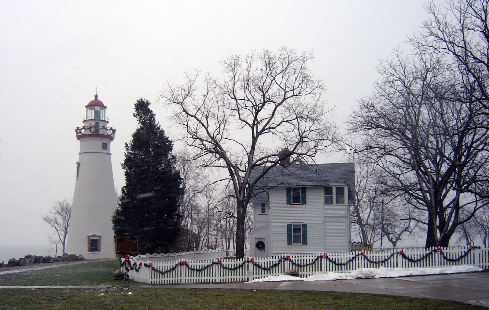 White lighthouse and keeper's house with holiday decorations