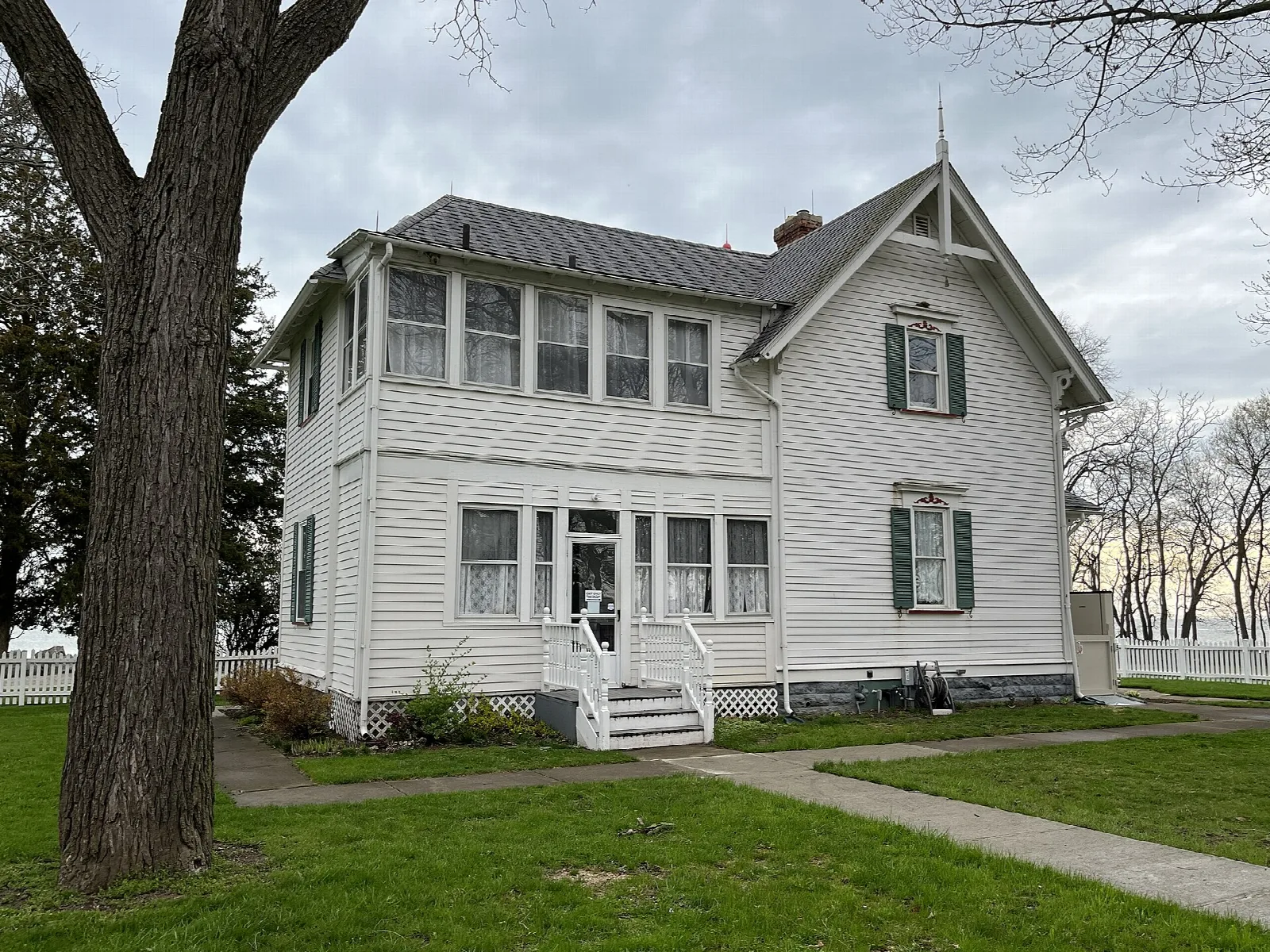 White two-story house with a lawn and a large tree