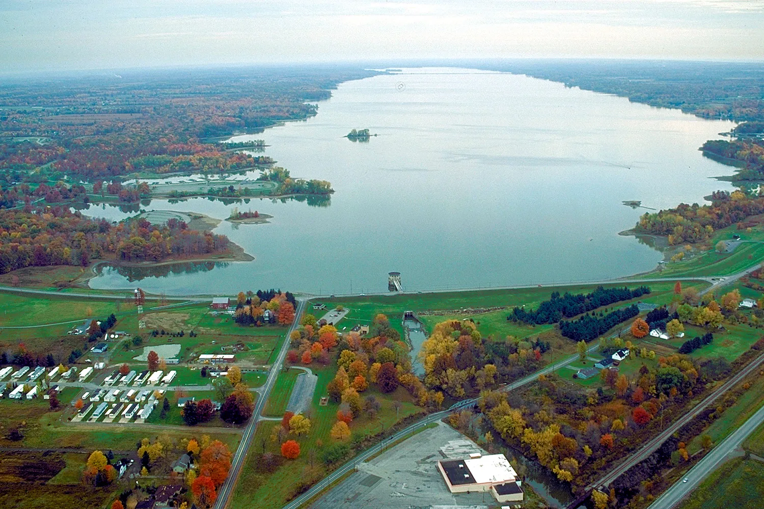 Aerial view of a long lake with autumn trees and a small town beside it