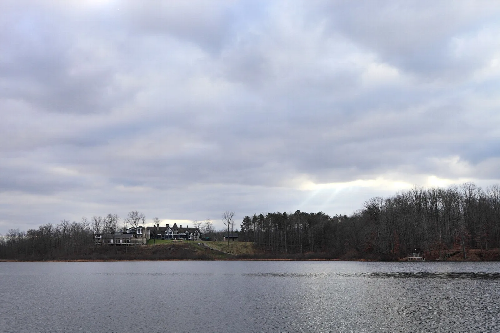 Lake under a cloudy sky with the manor visible on the far shore