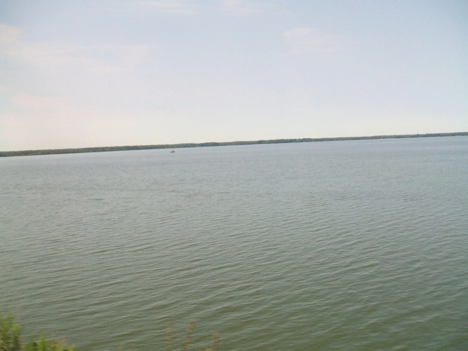 Wide calm lake stretching to a tree-lined horizon